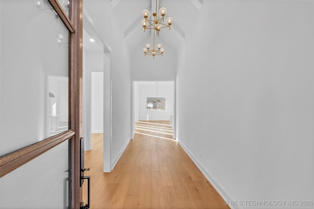 hallway with high vaulted ceiling, beamed ceiling, a chandelier, and light wood-type flooring