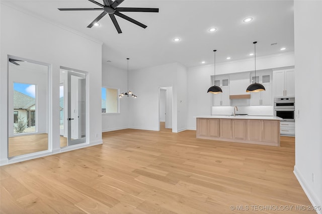 kitchen featuring ceiling fan with notable chandelier, white cabinetry, an island with sink, light hardwood / wood-style floors, and light brown cabinetry