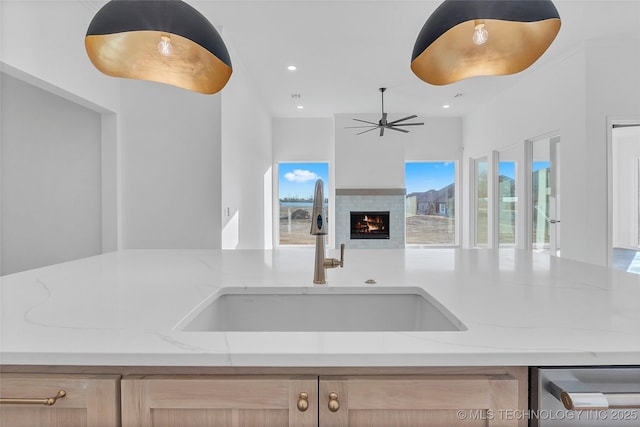 kitchen with light stone counters, sink, and light brown cabinets