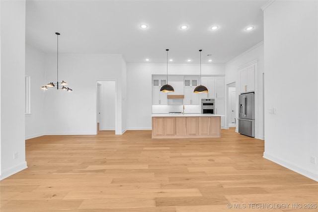 kitchen with a center island with sink, white cabinetry, light hardwood / wood-style flooring, hanging light fixtures, and stainless steel appliances