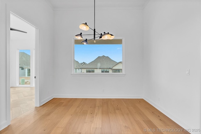 unfurnished dining area with crown molding, hardwood / wood-style floors, and a notable chandelier