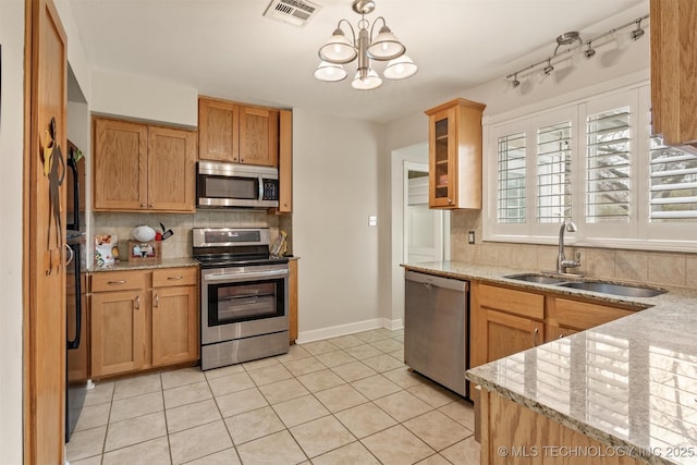 kitchen featuring sink, an inviting chandelier, light stone counters, light tile patterned flooring, and appliances with stainless steel finishes