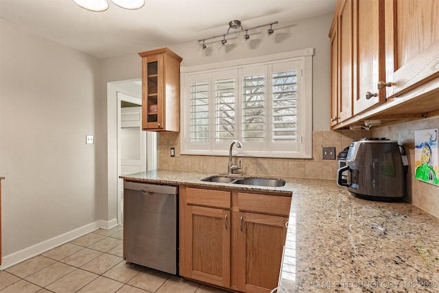 kitchen with stainless steel dishwasher, backsplash, light stone counters, and sink