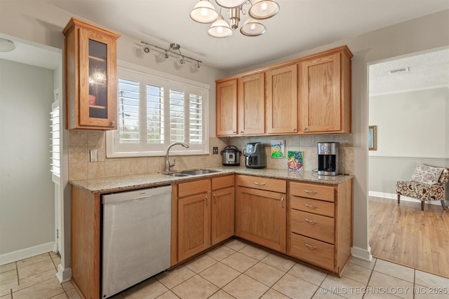 kitchen featuring dishwasher, sink, decorative backsplash, light tile patterned floors, and a notable chandelier