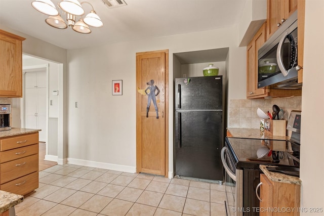 kitchen featuring a chandelier, light stone countertops, light tile patterned flooring, and stainless steel appliances