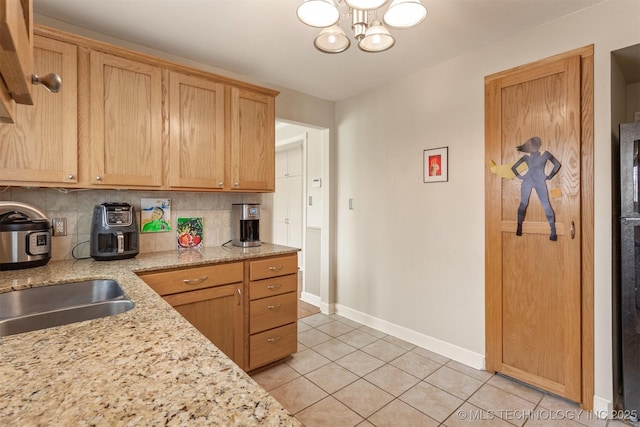 kitchen featuring decorative backsplash, light tile patterned floors, light stone countertops, and a notable chandelier