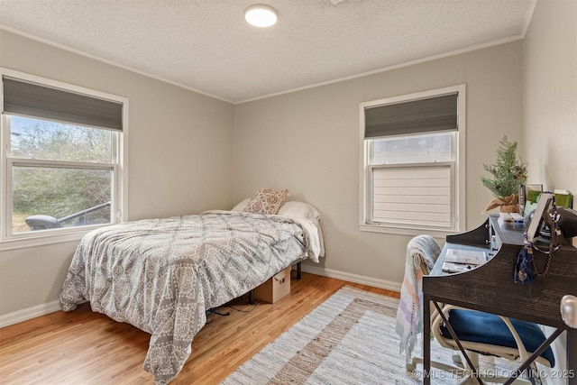 bedroom featuring crown molding, a textured ceiling, and light wood-type flooring