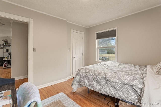 bedroom featuring wood-type flooring, a textured ceiling, and ornamental molding