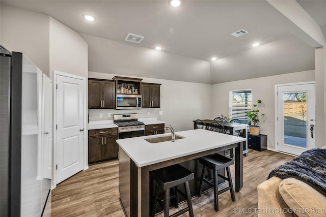 kitchen featuring appliances with stainless steel finishes, a breakfast bar, sink, lofted ceiling, and an island with sink