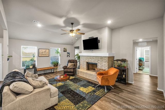 living room featuring hardwood / wood-style floors, ceiling fan, lofted ceiling, and a fireplace