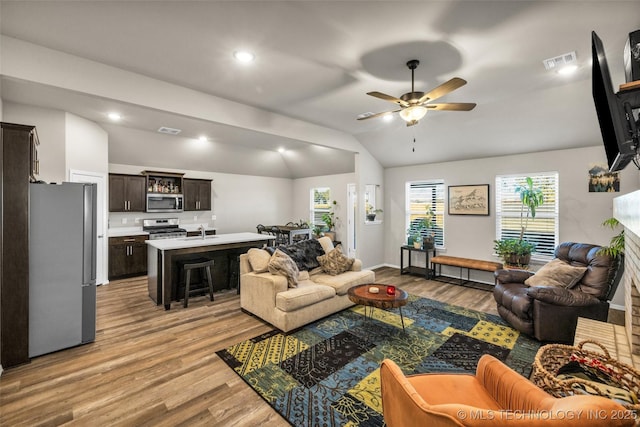 living room featuring ceiling fan, sink, light hardwood / wood-style floors, and lofted ceiling