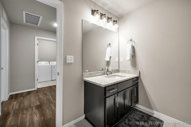 bathroom with wood-type flooring, vanity, and washer and clothes dryer