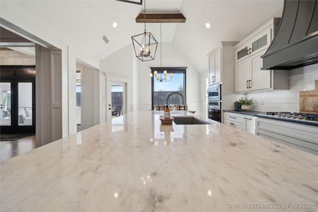 kitchen with decorative light fixtures, premium range hood, light stone countertops, stainless steel appliances, and white cabinets