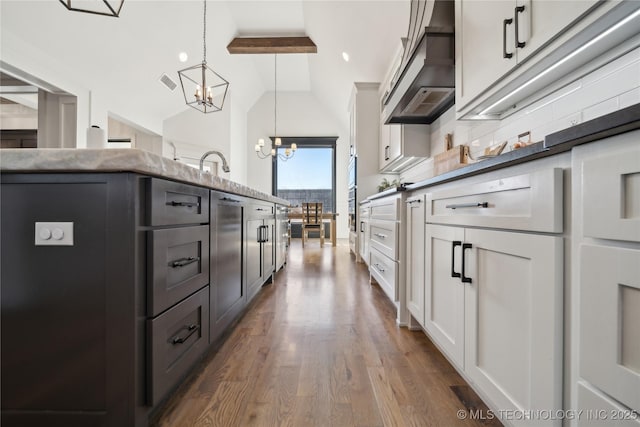 kitchen featuring pendant lighting, lofted ceiling with beams, an inviting chandelier, white cabinets, and dark hardwood / wood-style flooring