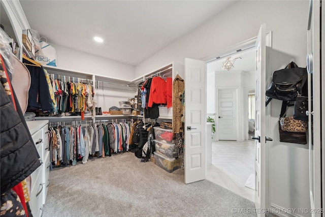 walk in closet with light carpet