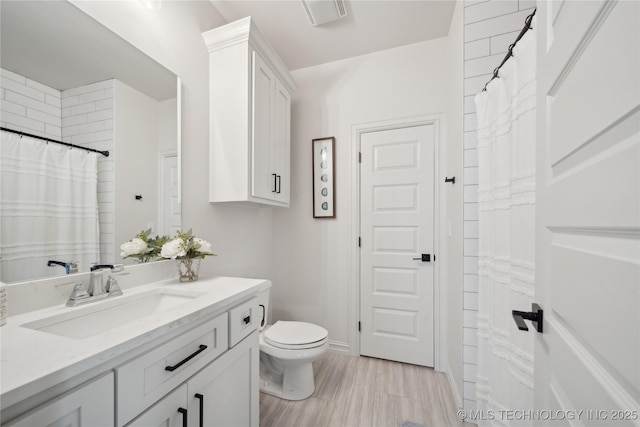 bathroom featuring toilet, wood-type flooring, and vanity