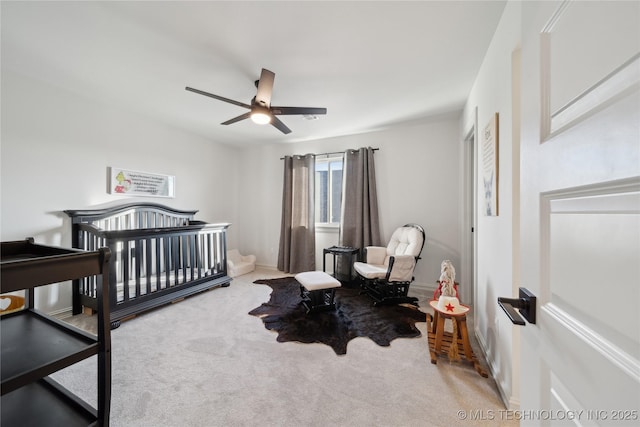 carpeted bedroom with ceiling fan and a crib