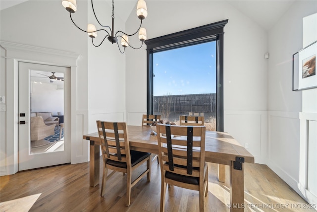 dining area featuring lofted ceiling, ceiling fan with notable chandelier, and hardwood / wood-style floors