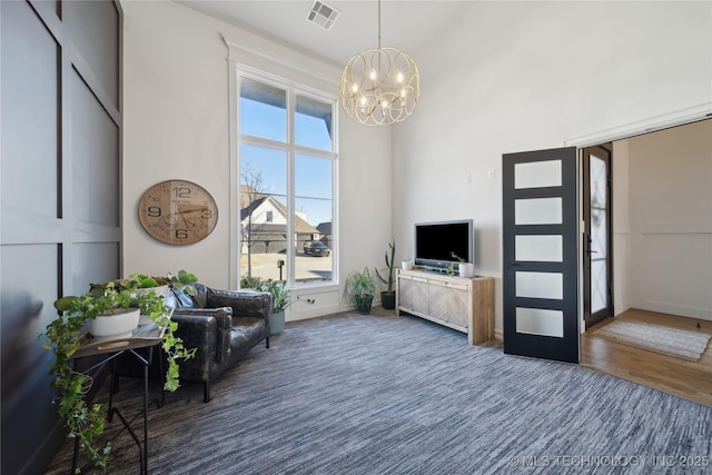 living room with dark wood-type flooring, a towering ceiling, and a notable chandelier