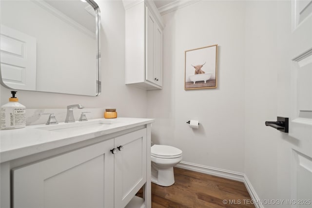 bathroom featuring hardwood / wood-style flooring, toilet, vanity, and crown molding