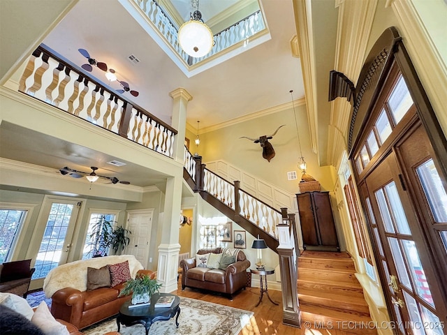 living room with ornate columns, ceiling fan, light hardwood / wood-style flooring, and a towering ceiling