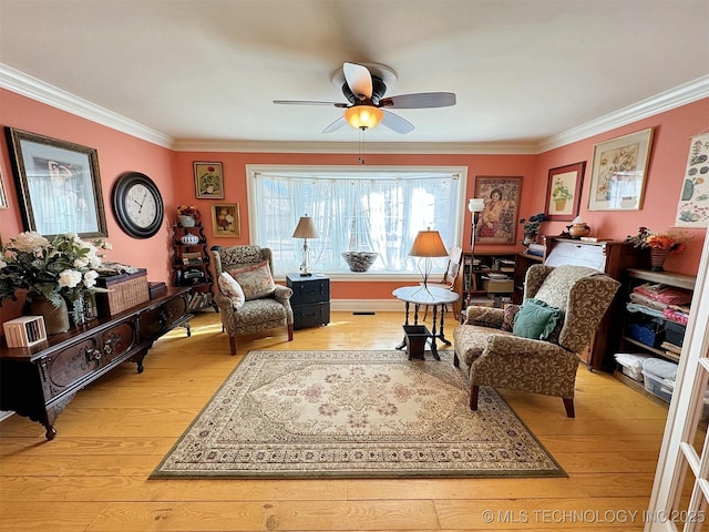 sitting room with hardwood / wood-style floors, ceiling fan, and crown molding