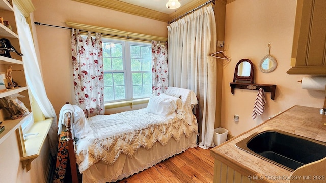 bedroom featuring light hardwood / wood-style floors, ornamental molding, and sink