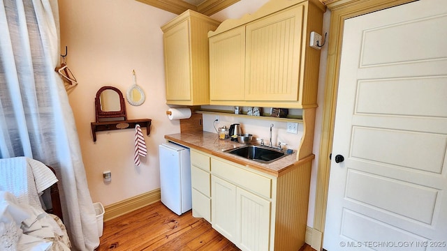 bar featuring sink, tile counters, crown molding, white dishwasher, and light hardwood / wood-style floors