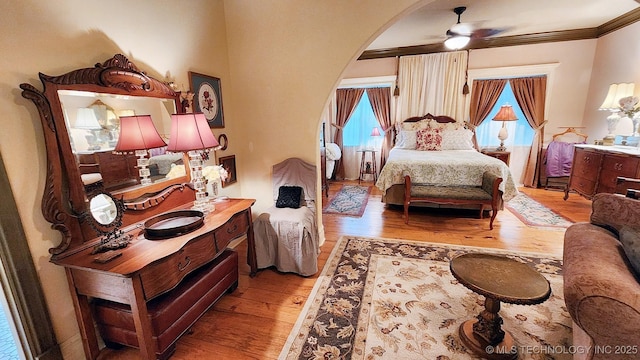 bedroom with wood-type flooring, ceiling fan, and ornamental molding