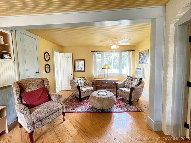 living area with a wall mounted AC, ceiling fan, hardwood / wood-style floors, and wood ceiling