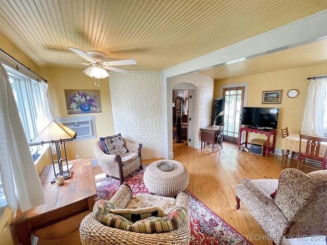 living room with a wall mounted air conditioner, ceiling fan, light hardwood / wood-style floors, and wooden ceiling