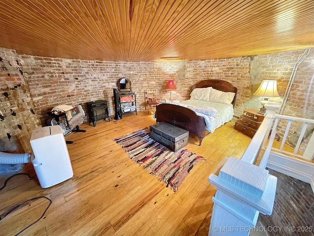 unfurnished bedroom featuring hardwood / wood-style floors, wood ceiling, and brick wall