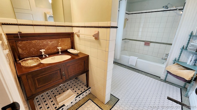 bathroom with tile patterned flooring, vanity, tiled shower / bath, and tile walls