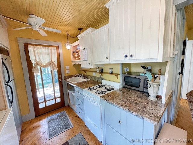 kitchen featuring white cabinetry, sink, hanging light fixtures, light hardwood / wood-style flooring, and appliances with stainless steel finishes