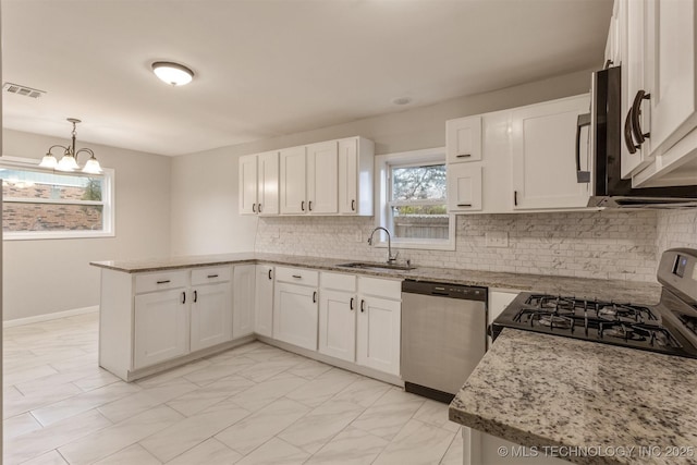 kitchen featuring light stone counters, stainless steel appliances, sink, pendant lighting, and white cabinets