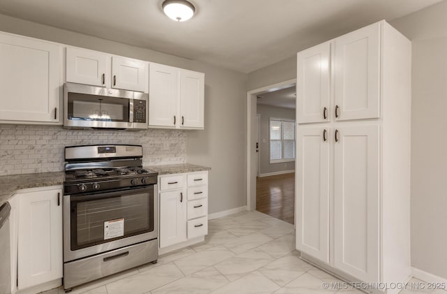 kitchen featuring white cabinets, light stone countertops, stainless steel appliances, and tasteful backsplash