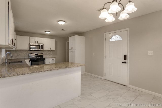 kitchen featuring kitchen peninsula, stainless steel appliances, sink, pendant lighting, and white cabinets