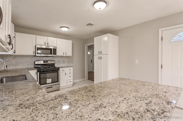 kitchen with white cabinets, stainless steel appliances, kitchen peninsula, and sink