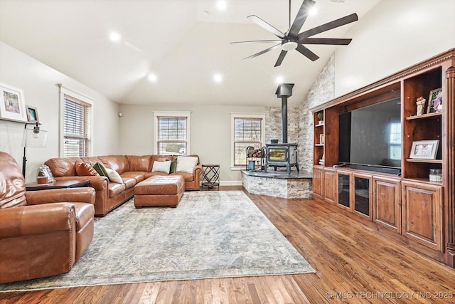 living room featuring a wood stove, plenty of natural light, wood-type flooring, and vaulted ceiling