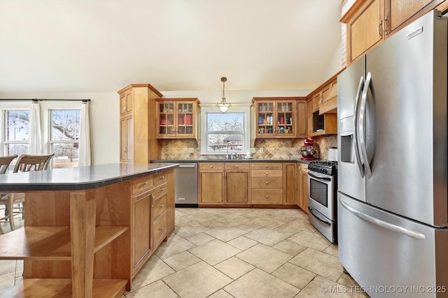 kitchen featuring sink, hanging light fixtures, a kitchen breakfast bar, backsplash, and appliances with stainless steel finishes