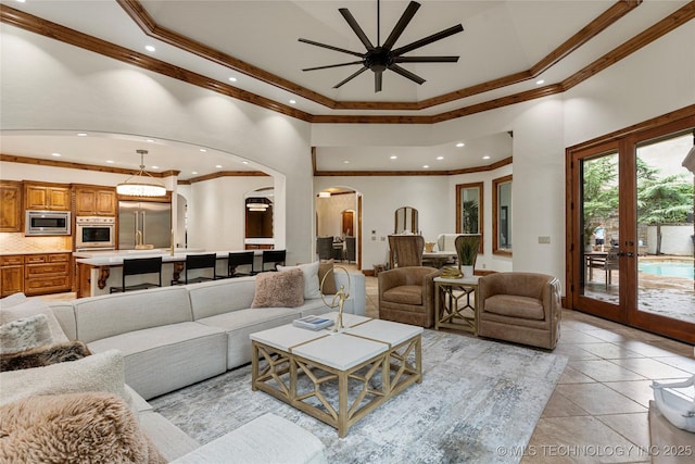 tiled living room with ceiling fan, french doors, a high ceiling, and ornamental molding