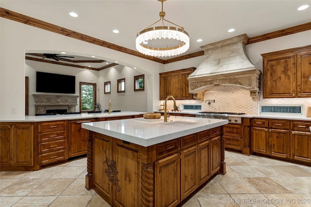 kitchen with stainless steel gas stovetop, sink, an island with sink, tasteful backsplash, and custom range hood