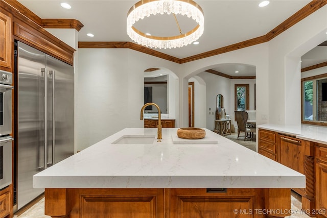 kitchen with a kitchen island with sink, stainless steel built in fridge, sink, and ornamental molding