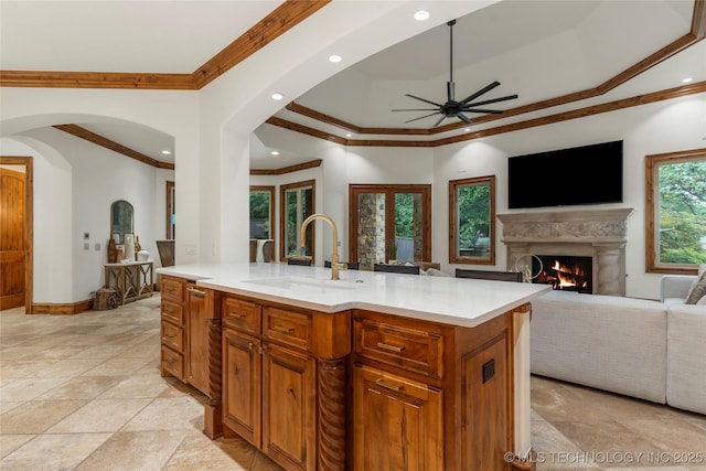 kitchen featuring ceiling fan, sink, ornamental molding, and a kitchen island with sink