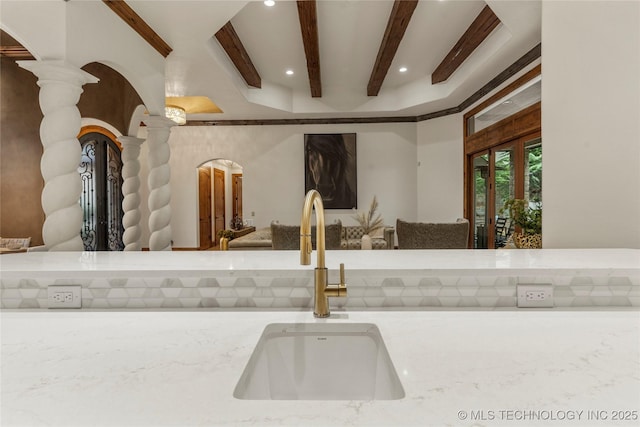 room details featuring rustic walls, french doors, sink, and decorative columns