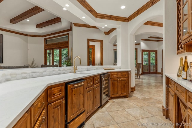 kitchen with french doors, crown molding, sink, light stone countertops, and beverage cooler