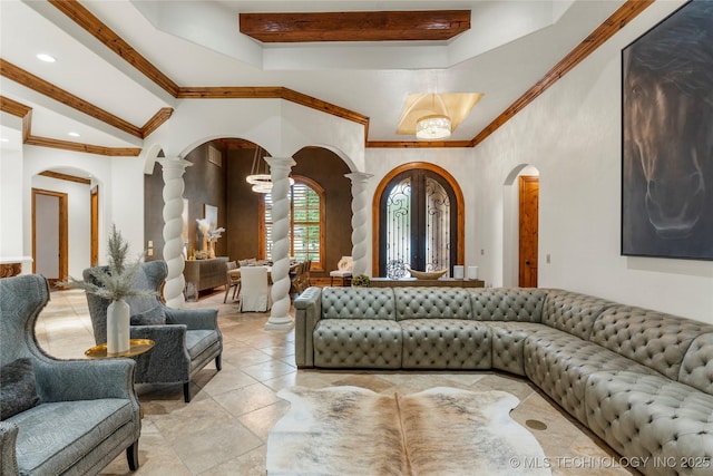 living room with decorative columns, a raised ceiling, crown molding, and french doors