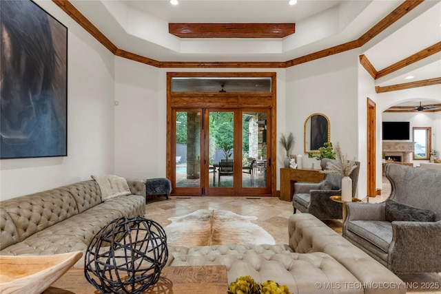 living room with ceiling fan, ornamental molding, french doors, and a tray ceiling