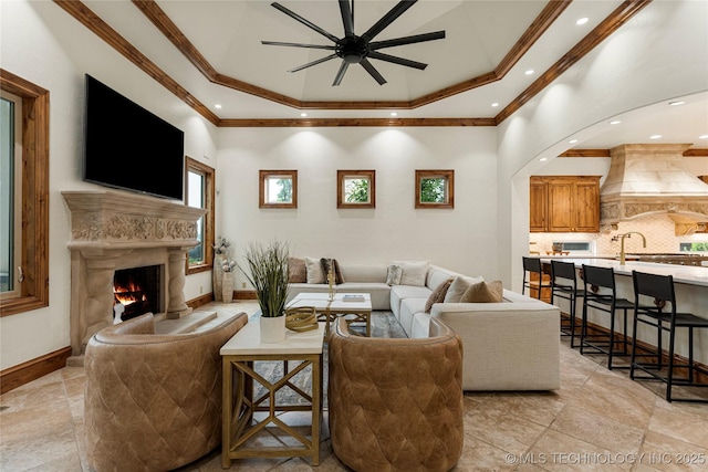 living room with a tray ceiling, ceiling fan, and ornamental molding