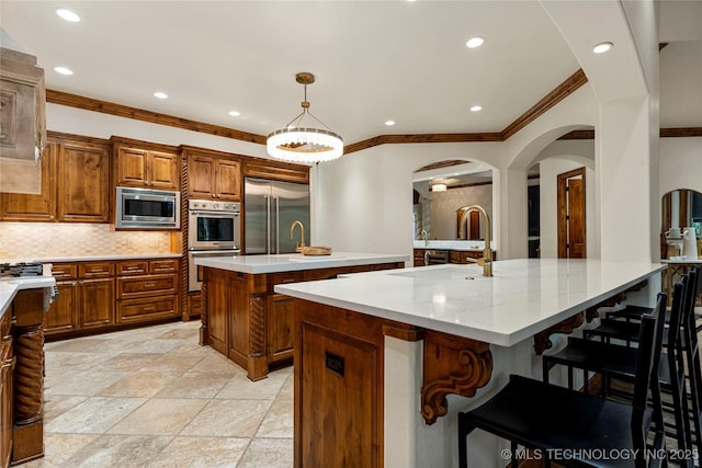 kitchen featuring a kitchen breakfast bar, a spacious island, built in appliances, tasteful backsplash, and decorative light fixtures